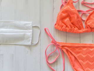 orange bikini and surgical mask to protect yourself in the pool or beach on vacation
