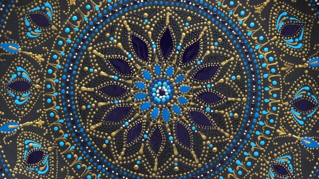 Decorative ceramic plate with black, blue and golden colors, painted plate on background, closeup, top view, rotate. Decorative porcelain plate painted with acrylic paints, handwork, dot painting