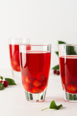 Summer delicious refreshing cherry compote with pulp and with ice in glasses on a white background