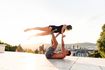 Beautiful man and two women doing acroyoga in the city. Harmony and relaxation with urban view