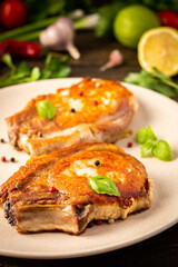 Fried pork entrecote on the bone, cooked pieces of pork meat with basil leaves and spices, steak on the bone in a plate on a wooden background