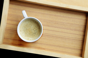 Coffee cup with crema on wooden background, top view with copy space.