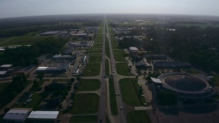 Aerial Drone Shot. Flying Down a Highway. Cars, Buildings, Small Stadium and Trees.
