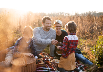 Beautiful young family with small children having picnic in autumn nature.