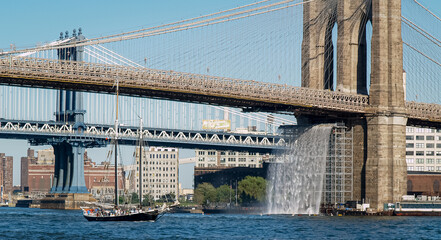 The Brooklyn Bridge as it crosses the East River between Manhattan and Brooklyn on to Long Island in New York City .