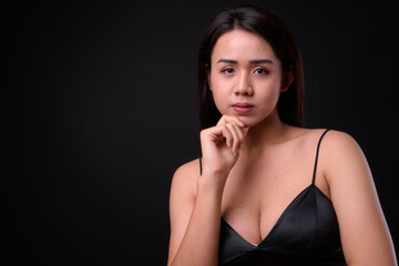 Young beautiful Asian transgender woman against black background