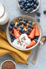 Granola bowl with berries and yogurt on concrete background. Healthy breakfast food top view vertical orientation