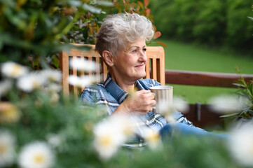 Senior woman with coffee sitting on terrace in summer, resting.