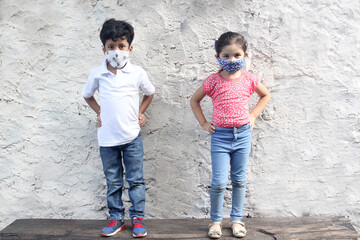 6-year-old boy and girl with covid-19 virus protection masks, on white wall background, new normal