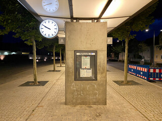 Moderner Bahnhof mit Betonwand und analoger runder leuchtender Uhr