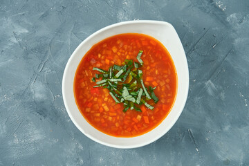 Classic vegetarian vegetable minestrone soup in a white bowl on a concrete background. Top view