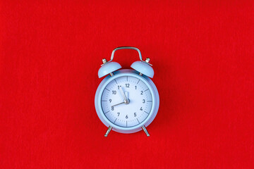 Blue retro alarm clock on red background with copy space. Concept of time, 5 minutes to 12, until...