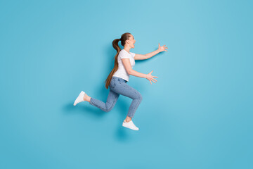 Fototapeta na wymiar Full length profile side photo of excited energetic girl jump run want hug long wait friend wear white t-shirt sneakers isolated over blue color background