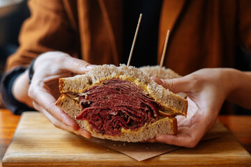 Faceless person holding classic Reuben meat sandwich