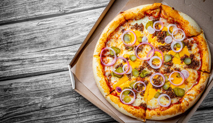Pizza with Mozzarella cheese, Bolognese sauce, minced meat and vegetables. Italian pizza in paper box on wooden background.