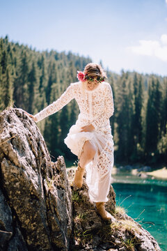 beautiful stylish woman in white lace dress climbs on a stone rock