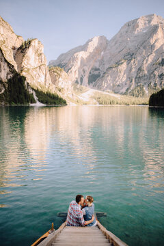 Beautiful Couple In Love Hugs And Kisses Sitting On Wooden stairs on background of beautiful mountain lake