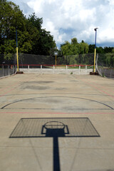 The shadow of a basketball hoop on a beach basketball court