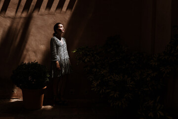 Young female standing by wall in darkness