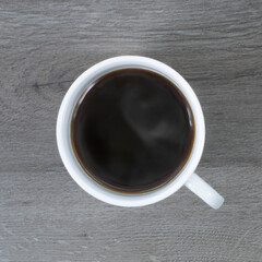 Grains of coffee with a cup of coffee on a dark wood background.