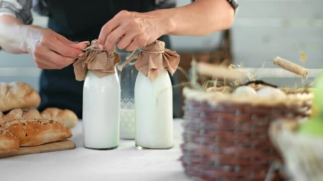 Female farmer hands packaging bottles of homemade milk tie rope. Close up shot on 4k RED camera