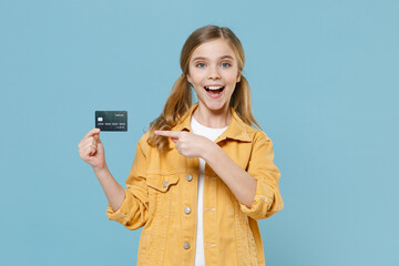 Excited little blonde kid girl 12-13 years old in yellow jacket isolated on pastel blue background...