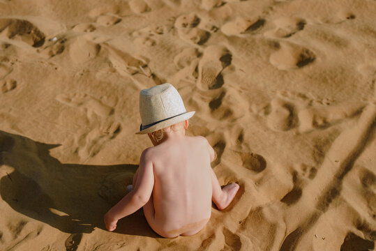 Baby boy plays with sand at the beach