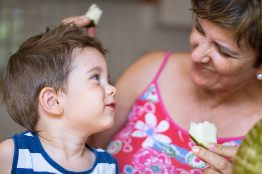 Little boy eating with his grandmother in the kitchen