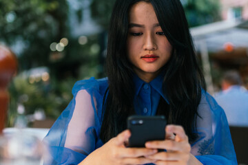Selective focus on a asian young woman holding a smartphone
