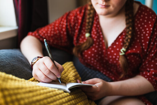 Selective focus of a woman with her hair in braids writting