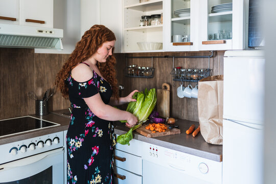 side view of a red haired woman preparing a dinner salad