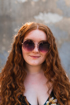 close up of a smiling woman with her red hair down in sunglasses