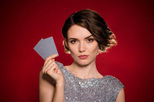 Closeup photo of attractive lady professional casino player hold two cards risky gamer all in cheating calm facial expression wear shine dress isolated dark red gradient color background