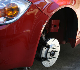 Front drivers side of a red car with the wheel removed showing a drilled and slotted brake rotor