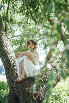 A young girl lies on a tree branch