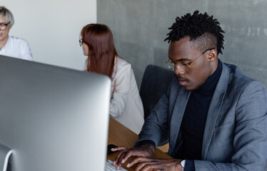 Focused African American employee typing on computer at workplace