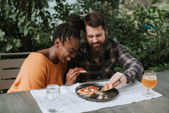 Cute Couple Eating Pizza at Outdoor Table
