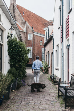 Man and his dog walking through a small historical alley