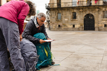 Couple of pilgrims seated in a bench reading a map in Astorga City on their way to Santiago de Compostela
