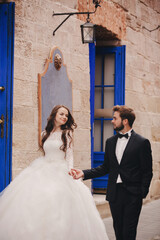 Wedding couple hugging in the old city. Blue vintage doors and cafe in ancient town on background....