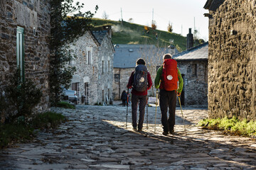 Couple of pilgrims walking along rural village in their way to Santiago de Compostela
