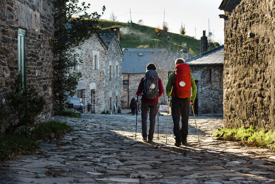 Couple of pilgrims walking along rural village in their way to Santiago de Compostela