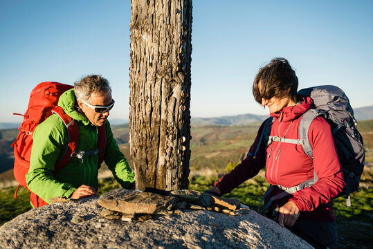 Couple of pilgrims close to a wooden cross at the top of Alto do Cebreirol in Saint James Way