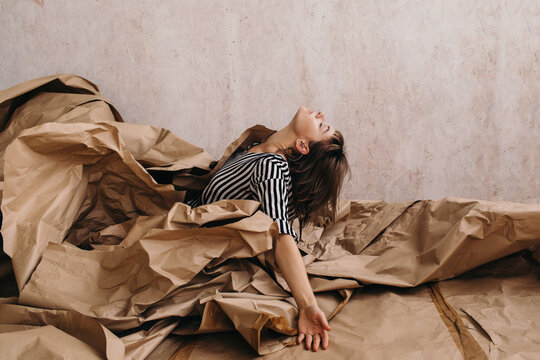 Creative carefree woman emerging from pile of craft paper