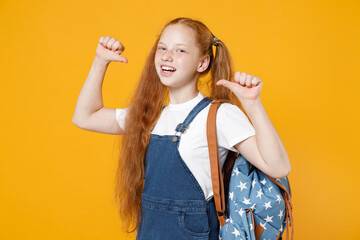 Young redhead school teen girl 12-13 years old pony tails in white t-shirt blue denim uniform backpack isolated on yellow background children studio portrait Childhood kids education lifestyle concept
