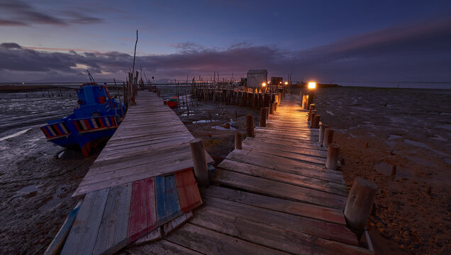 Sunset landscape of artisanal fishing boats in the old wooden pier.