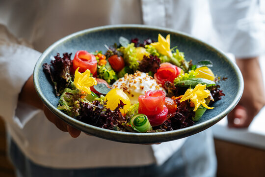 Person holding plate with bright appetizing salad