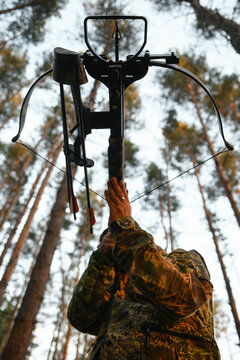Adult man hunting with a recurved crossbow in the forest on an autumn day.