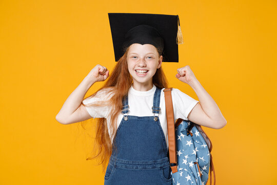 Young redhead school teen girl 12-13 years old in white t-shirt denim uniform graduation cap backpack isolated on yellow background children studio portrait Childhood kids education lifestyle concept
