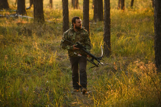 Adult man hunting with a recurved crossbow in the forest on an autumn day.